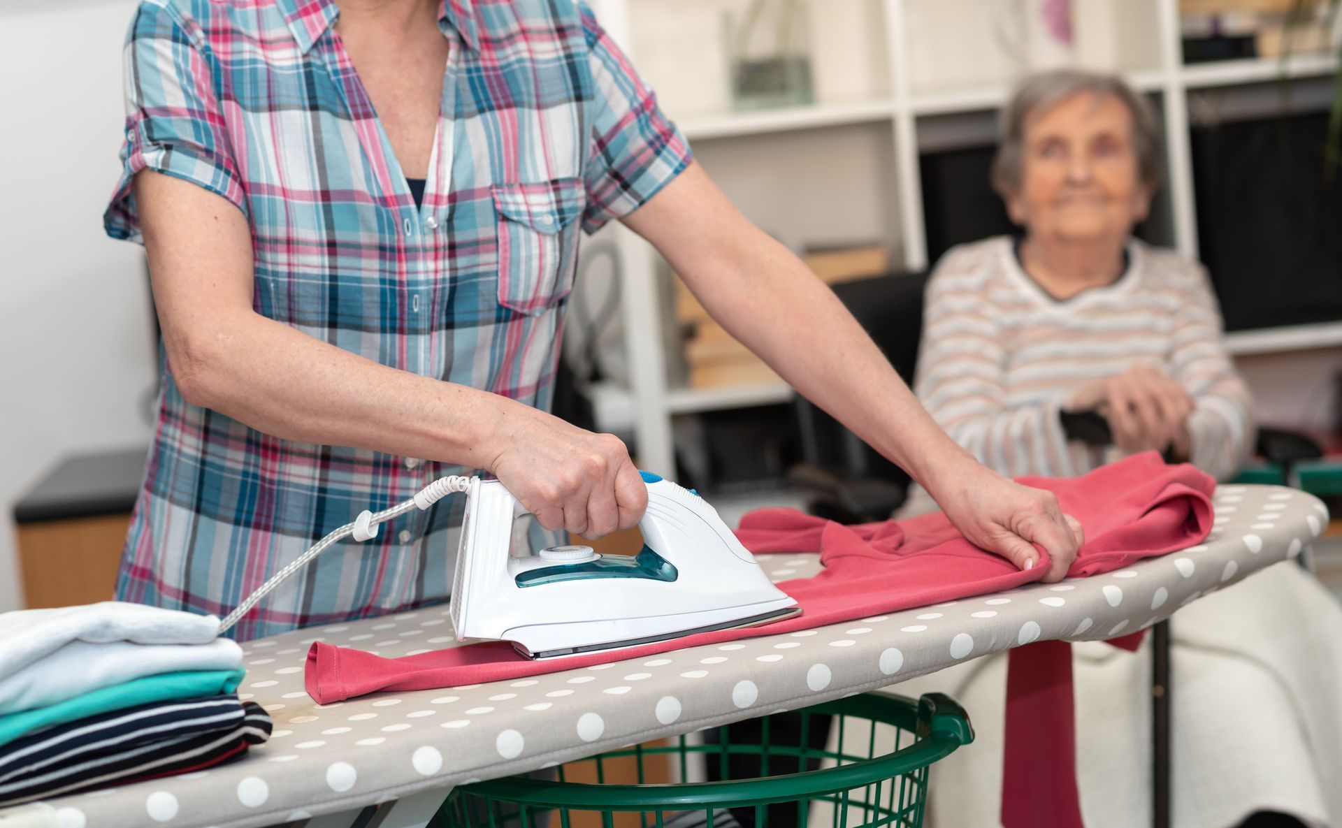 Aide à domicile faisant le repassage d'une dame âgée
