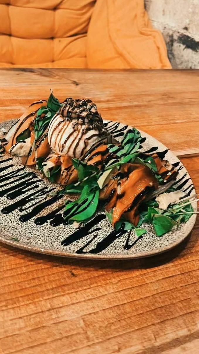 Plato de comida con rúcula, berenjena frita y glaseado balsámico.