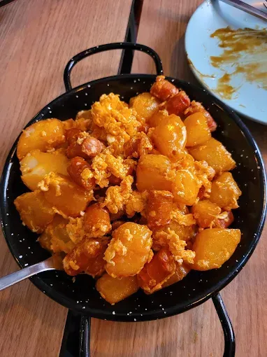 Plato de patatas con chorizo ​​y pan rallado en sartén negra.
