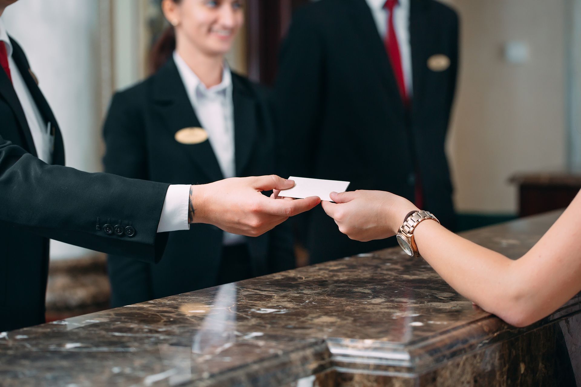 Un huésped del hotel entrega una tarjeta de presentación a un miembro del personal del hotel en la recepción.