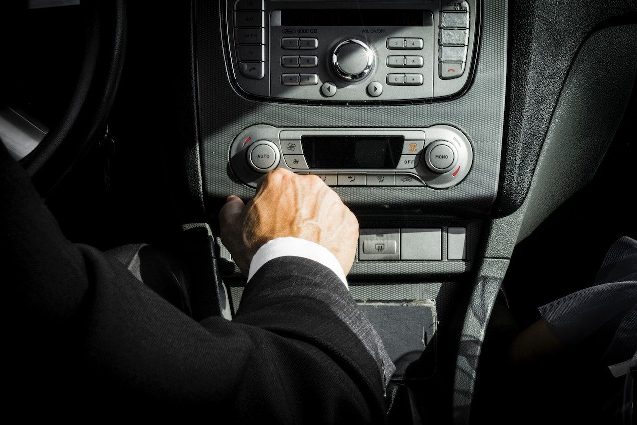 Una persona con traje ajusta la radio de un automóvil.