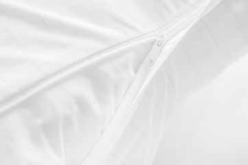 Primer plano de ropa de cama blanca con una cremallera parcialmente abierta, resaltando la tela texturizada y los detalles de las costuras.
