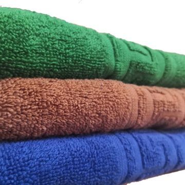 Tres toallas enrolladas: verde, marrón y azul, apiladas una encima de otra.