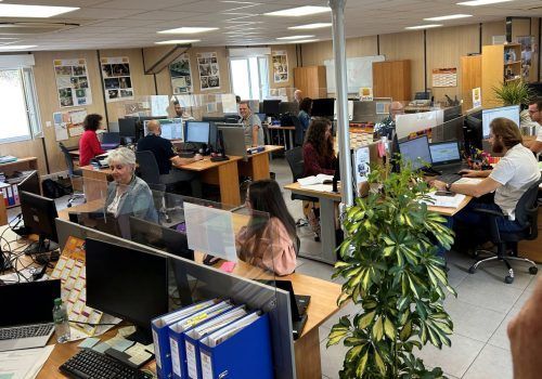 Espace de travail de bureau avec plusieurs personnes à des bureaux avec des ordinateurs.