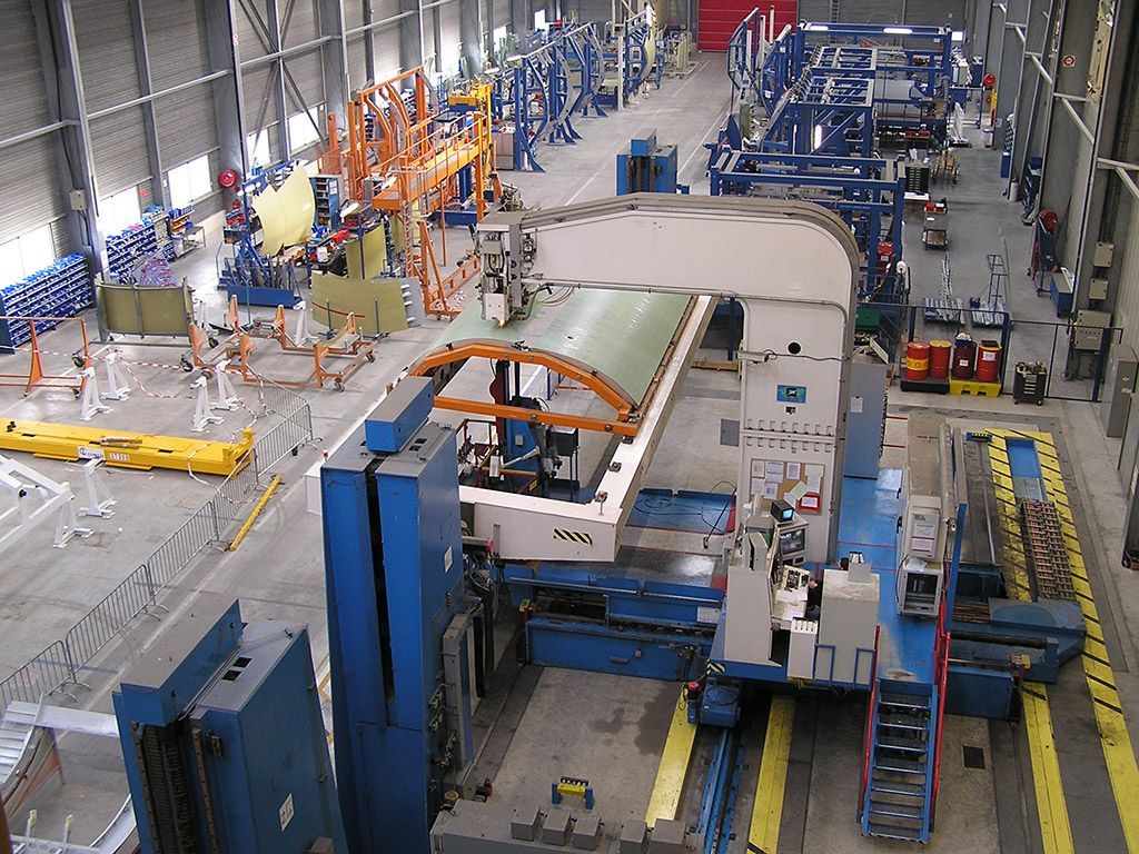 Grande usine avec des machines industrielles assemblant des pièces d'avion.
