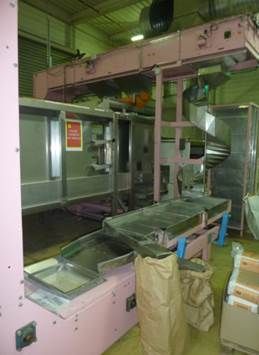 Machine industrielle de transformation alimentaire rose avec bandes transporteuses et goulotte en spirale, à l'intérieur.