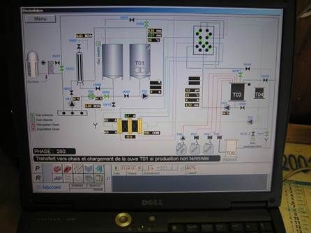 Écran d'ordinateur portable montrant un schéma d'équipement industriel avec réservoirs, tuyaux et commandes.