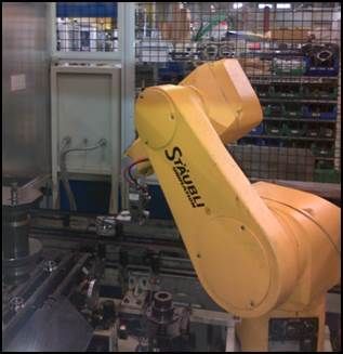 Bras robot industriel jaune Stäubli dans une usine, manipulant des objets.