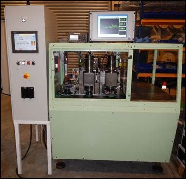 Machine industrielle avec panneau de commande et affichage, enfermée dans une armoire verte.