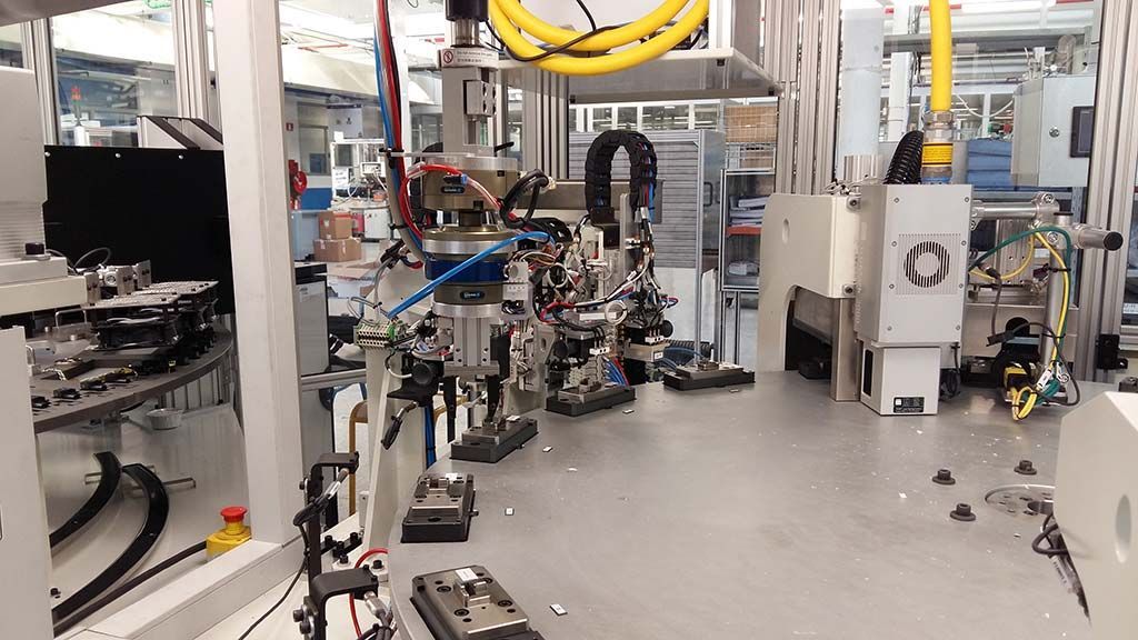 Bras robotisés travaillant sur une chaîne de montage dans une usine, avec machines et outils.