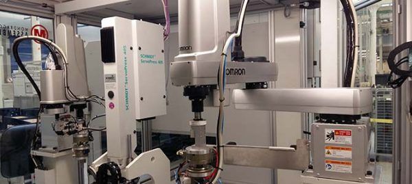 Bras robotisés dans un environnement industriel automatisé, semblant manipuler des pièces.