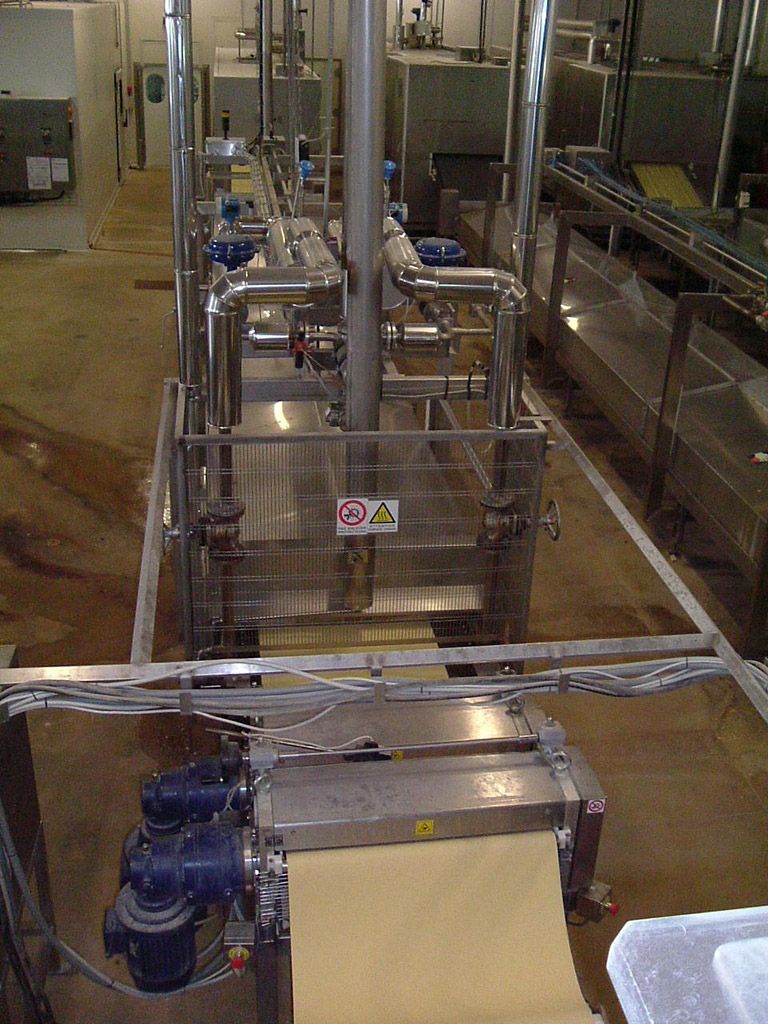 Machines de transformation alimentaire industrielle avec réservoirs, tuyaux et pompes en acier inoxydable dans une usine.