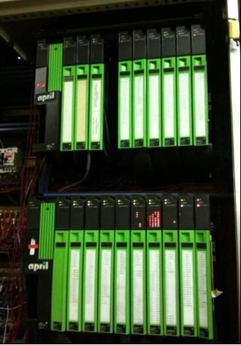 Panneau de contrôle électrique vert avec plusieurs modules et câblage dans une armoire.