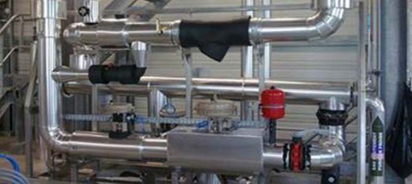 Système de tuyauterie industrielle complexe avec diverses vannes, jauges et isolations.