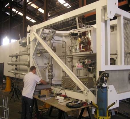 Un homme travaille sur une grande machine industrielle blanche à l'intérieur d'un entrepôt.