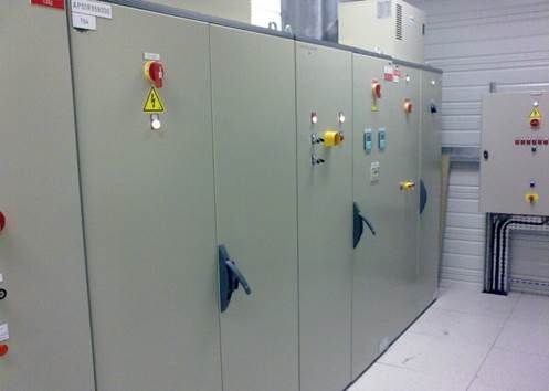 Tableaux de commande électriques dans une pièce, beiges avec divers interrupteurs et poignées.