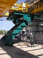 Un ouvrier se tient près d'une grande grue industrielle verte et jaune équipée d'une échelle. Vue intérieure.