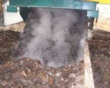 Machine à composter libérant de la vapeur sur un tas de matière organique, probablement dans une installation de compostage.