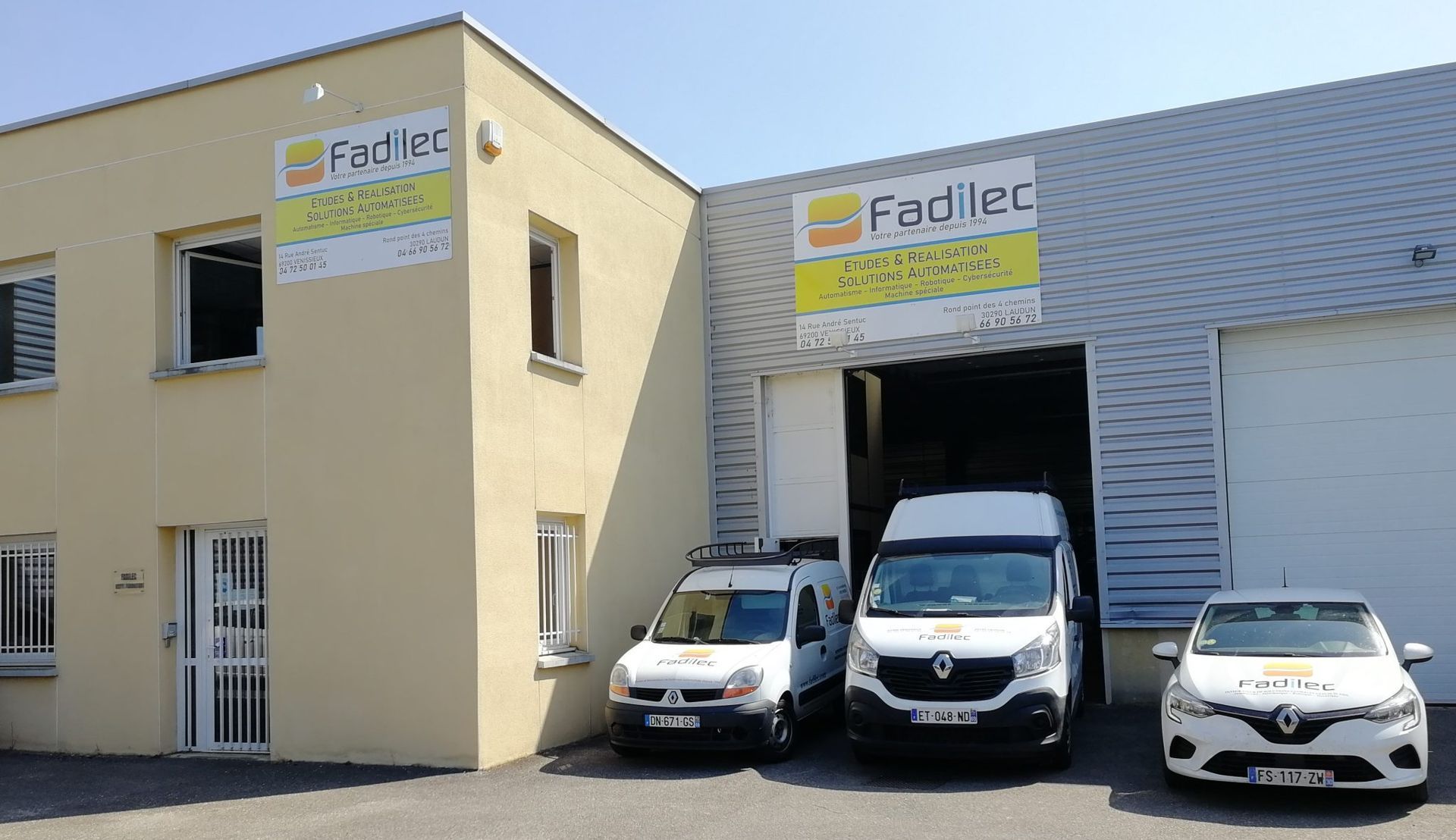 Bâtiment avec panneau « Fadiec » et trois véhicules d'entreprise garés à l'extérieur.