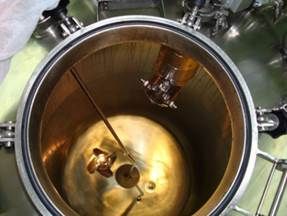 Vue intérieure d'un grand réservoir industriel avec des composants internes immergés dans un liquide brun.