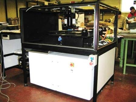 Machine avec dessus noir, armoire blanche et fils ; dans un atelier.