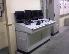 Panneau de contrôle avec quatre écrans, clavier, souris et commandes dans un réglage d'usine.