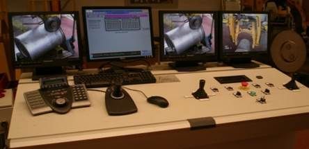 Panneau de contrôle avec quatre écrans affichant les équipements et commandes industriels.