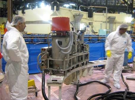 Deux ouvriers en costumes blancs près de machines complexes dans une usine.