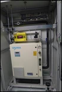 Système générateur d'ozone dans une armoire, avec panneau de commande jaune sur le dessus. Marque « OZONIA » visible.