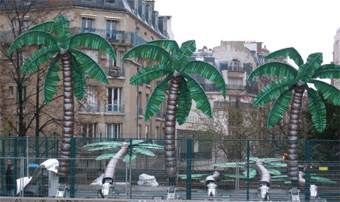 Palmiers devant des bâtiments ; une installation fantaisiste dans un cadre urbain.