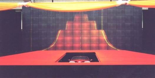 Voiture sur une plate-forme rouge, à l'intérieur d'une scène avec un grand écran éclairé en rouge.