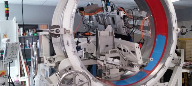 Une grande machine blanche avec une ouverture circulaire. Des bandes rouges et bleues sont visibles à l'intérieur.