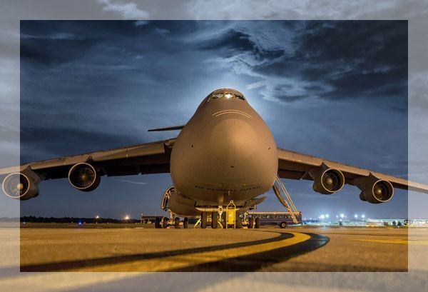 Avion de transport militaire C-5 Galaxy sur une piste la nuit, se découpant sur un ciel orageux.