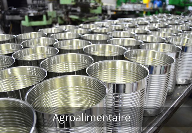 Des rangées de boîtes de conserve métalliques vides dans une usine.