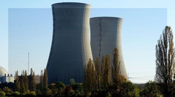 Deux grandes tours de refroidissement grises dans une centrale nucléaire, sous un ciel bleu.