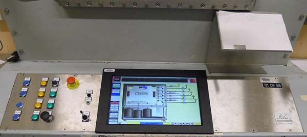 Panneau de commande avec boutons, écran affichant un schéma et un gros bouton d'arrêt rouge.