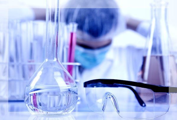 Scientifique en blouse et masque de laboratoire avec équipement de laboratoire, l'air fatigué, lunettes de sécurité au point.