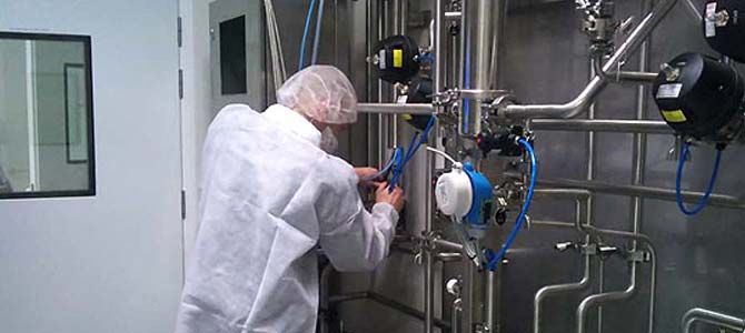 Personne en combinaison de protection travaillant sur des machines industrielles.