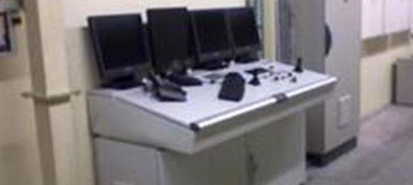 Un panneau de contrôle avec plusieurs moniteurs dans une pièce beige.