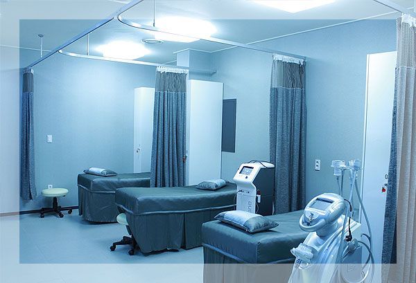 Salle d'examen avec lits, rideaux et matériel médical.