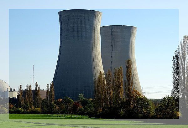 Deux grandes tours de refroidissement dans une centrale nucléaire contre un ciel bleu clair.