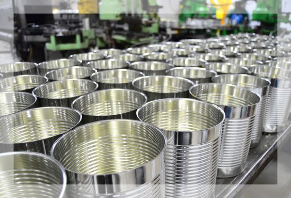 Des rangées de boîtes de conserve métalliques vides et brillantes sur une chaîne de production d'usine.