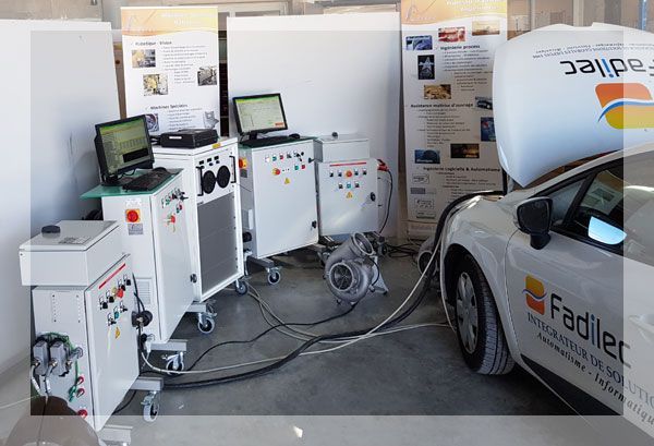 Voiture testée avec des machines connectées dans un garage. Voiture blanche, équipements blancs, ordinateurs et câbles.