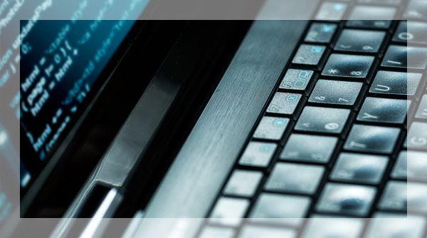 Clavier et écran d'ordinateur portable avec code, éclairés dans des tons froids.