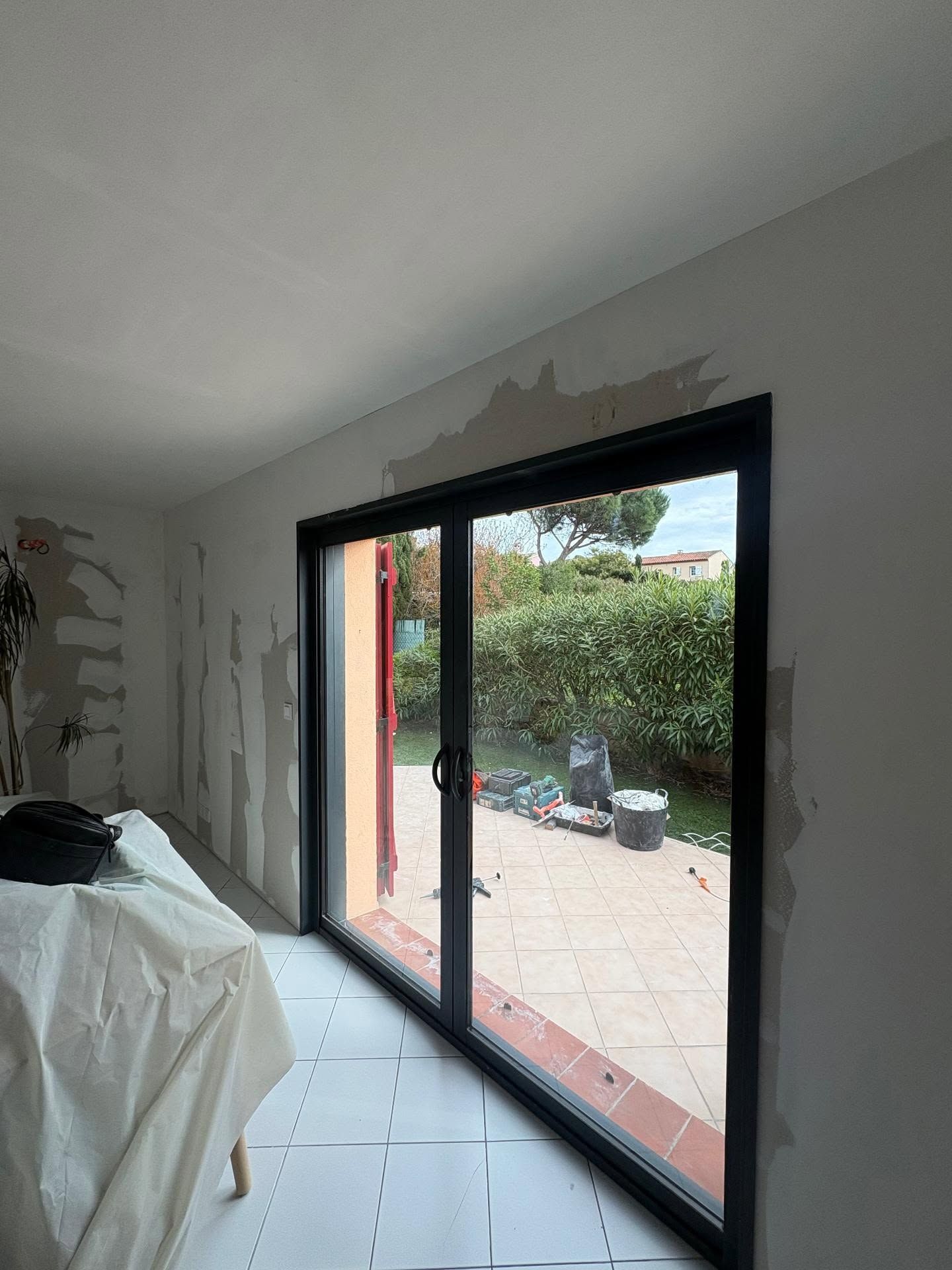 Pièce intérieure avec de grandes portes coulissantes en verre à cadre noir donnant sur un patio et un jardin.