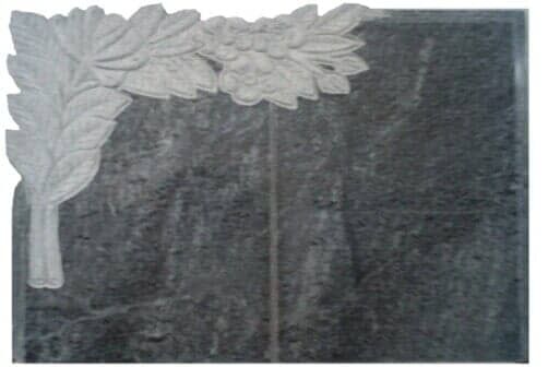 Lápide cinza-escura com desenho floral branco nos cantos.