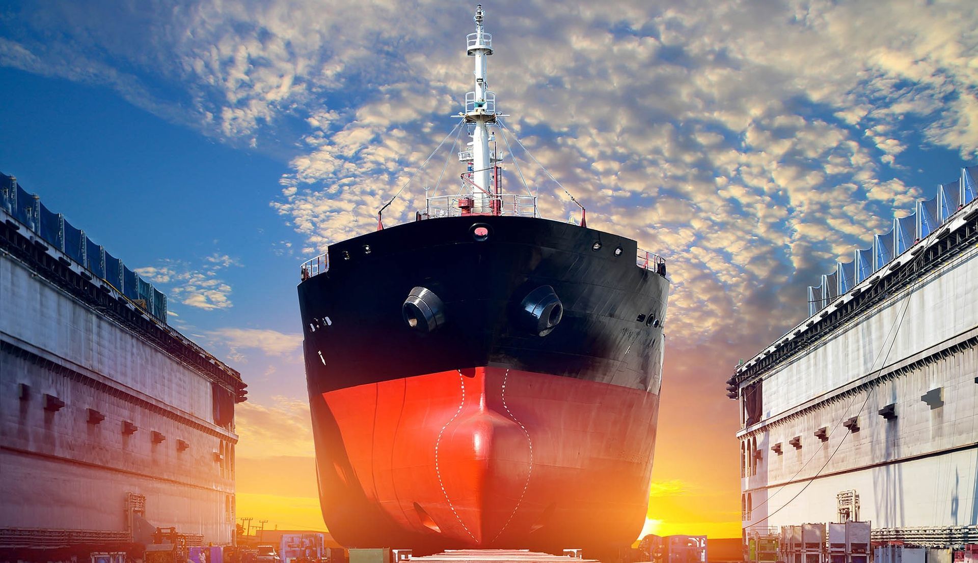 Se está construyendo un gran barco en un astillero al atardecer.