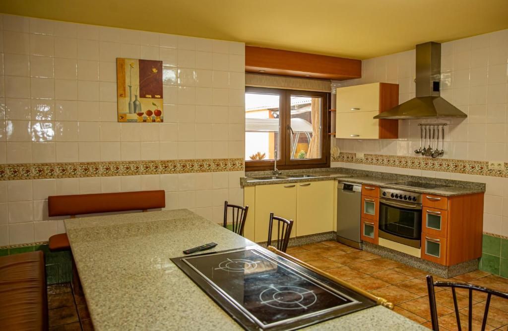Amplia cocina con paredes alicatadas, isla de granito, armarios de madera y una gran ventana sobre el fregadero.