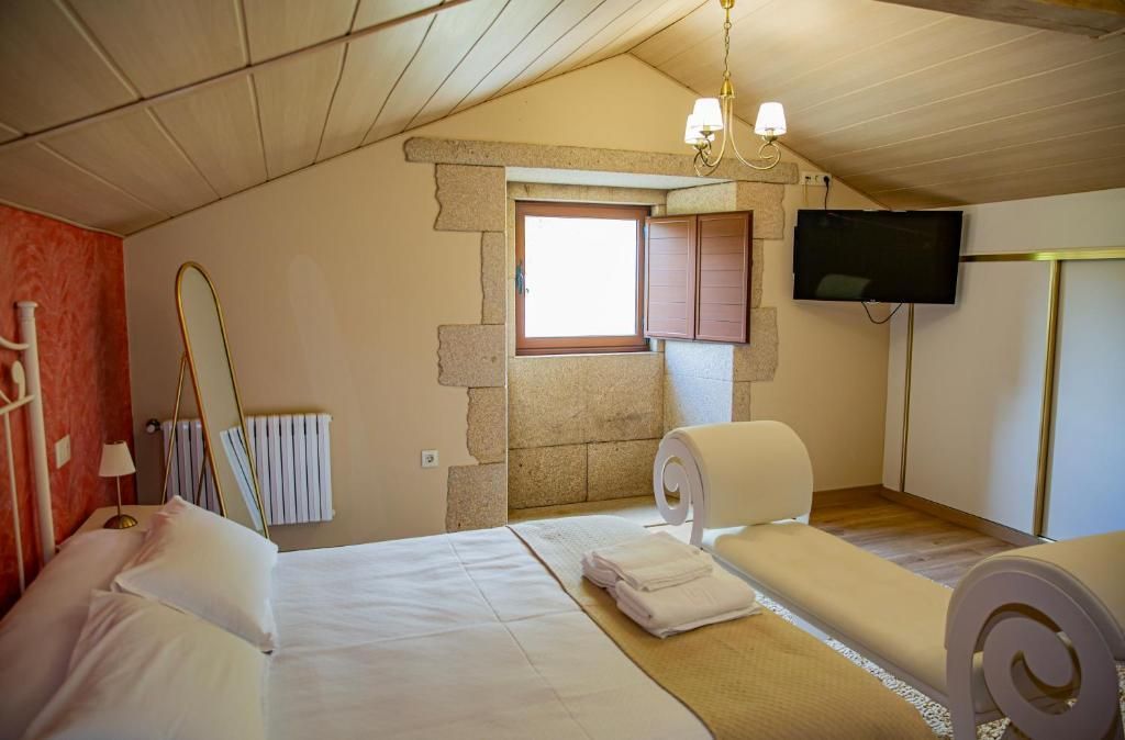 Acogedora habitación abuhardillada con dos camas, ventana, televisión y techo de madera inclinado.