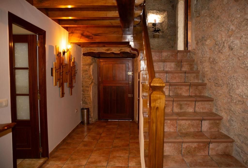Pasillo interior con escaleras de piedra, puertas de madera e iluminación cálida de color ámbar.